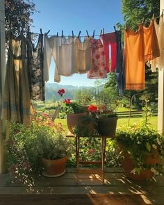 clothes hanging out to dry in the sun on a line with potted plants and flowers