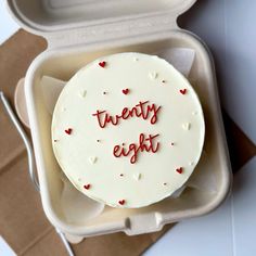 a white cake in a box with the words twenty eight written on it and hearts