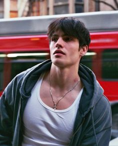 a young man standing in front of a red bus