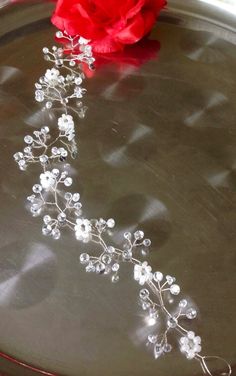 a red rose sitting on top of a metal tray next to a crystal beaded flower