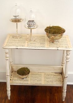 a table with two glass vases on top of it next to a wooden shelf