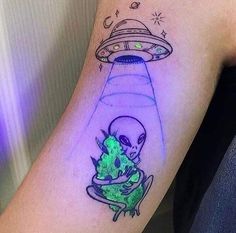 a tattoo with an alien on it and a spaceship in the sky above it, as well as a green plant