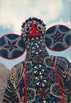 a cow statue is decorated with colorful patterns and circles on it's head, in front of mountains