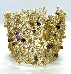 This intricately designed cuff bracelet has been crocheted with non tarnish brass wire and has a brass magnetic clasp.  Semi precious stones and glass beads have been interwoven throughout the design. This bracelet will complement any outfit and can be custom made to any size. MEASUREMENTS: Bracelet widths are: 5.5 cm, (2.16") 6 cm (2.36") and 6.5 cm (2.55"). The length of the bracelet will depend on your wrist measurement. Please measure the circumference of your wrist (not the size you want th Fusion Gold Beaded Jewelry, Fusion Style Gold Beaded Jewelry, Adjustable Gold Beaded Fusion Bracelets, Adjustable Gold Fusion Beaded Bracelets, Hand Wrapped Gold Jewelry For Parties, Gold Hand Wrapped Jewelry For Party, Gold Woven Bracelet Jewelry, Gold Hand-wrapped Beaded Bracelets For Party, Gold Hand Wrapped Beaded Bracelets For Party