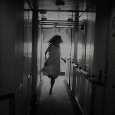 a woman walking down a hallway with her hair blowing in the wind and light coming through