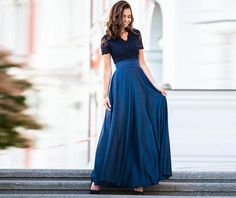 a woman in a long blue dress standing on steps