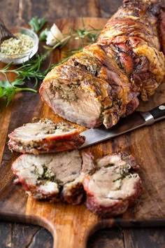 sliced meat on cutting board with knife next to it and garnished with herbs