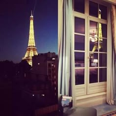 the eiffel tower is lit up at night in paris, france as seen from an apartment window