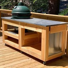 a large green egg sitting on top of a wooden table next to a bbq