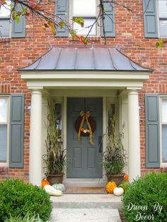 a front door with pumpkins and gourds on the steps