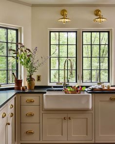 a kitchen with white cabinets, black counter tops and gold pulls on the windowsill