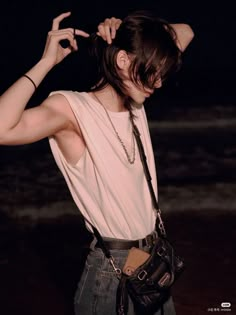 a woman standing on the beach with her hands behind her head