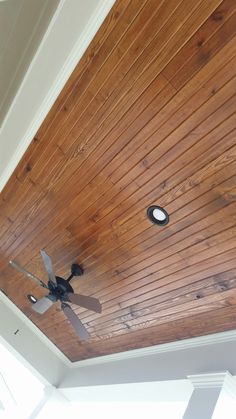 a ceiling fan mounted to the side of a wooden ceiling