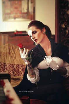 a woman sitting on a couch holding a rose in her right hand and wearing white gloves