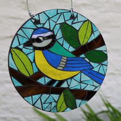 a stained glass bird hanging on a tree branch