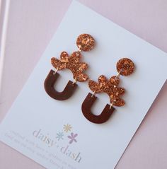 a pair of brown and gold earrings on top of a card