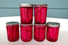 four jars filled with pickles sitting on top of a table