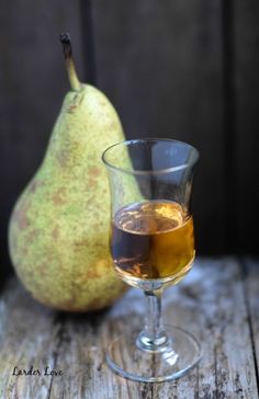 a pear sitting next to a glass filled with liquid