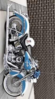 a blue and white motorcycle parked next to a wall