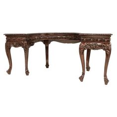 an antique wooden desk with carved wood legs and carvings on the top, against a white background