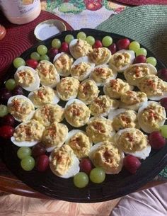 a platter filled with deviled eggs and grapes