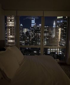 a bedroom with a view of the city at night