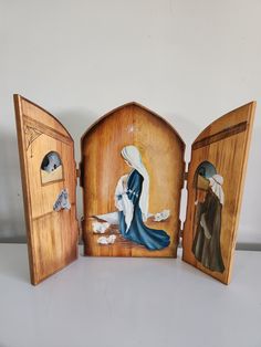 three wooden nativity scenes are displayed on a table