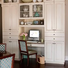 a desk and chair in a room with white cabinets