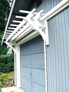 a gray garage with a white trellis over it