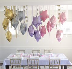 there are many different colored umbrellas hanging from the ceiling above the table and chairs