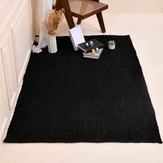 a black rug in the corner of a room with a chair and other items on it