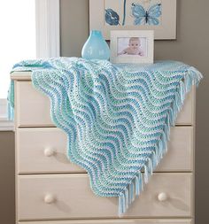 a blue crocheted blanket sitting on top of a dresser