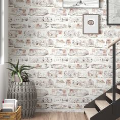 a white brick wall with stairs and pictures on the wall next to it in a living room