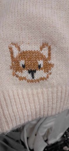 a close up of a knitted hat with a fox design on the front and side