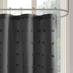 a black curtain hanging from a metal rod in front of a window with white curtains