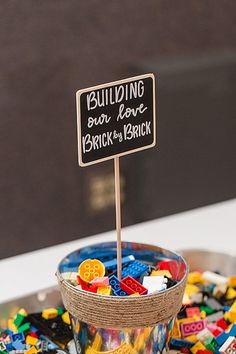 a bowl full of legos with a sign on top that says building fun for brickers