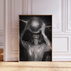 a black and white photo of a woman with a disco ball on her head in front of a wall