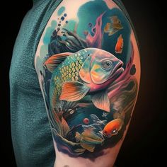 a man's half sleeve with colorful fish and corals on the side of his arm