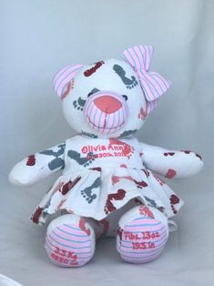 a white teddy bear with pink and gray stripes on it's face, sitting against a white background