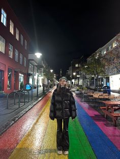 a woman standing in the middle of a rainbow painted street