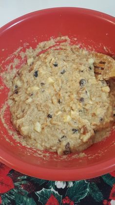 a red bowl filled with oatmeal sitting on top of a floral table cloth