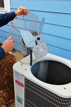 an air conditioner is being held up to the side of a house by a man