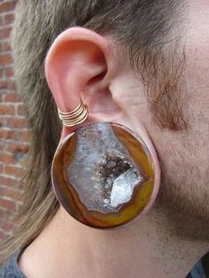 a close up of a person with ear piercings and an earring made out of agate stone