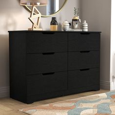 a black dresser sitting in front of a mirror on top of a wooden floor next to a rug