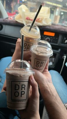 two people sitting in the back seat of a car holding up cups with straws