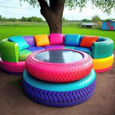 an unusual couch made out of old tires and other colorful furniture in a park setting