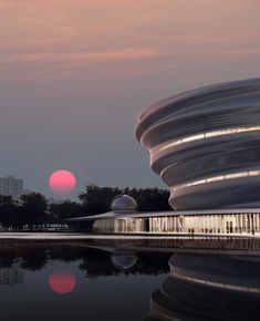 the sun is setting over an architectural building with water reflecting off it's surface