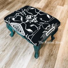 a black and white ottoman sitting on top of a wooden floor next to a chair