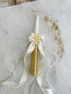 a white and gold ribbon wrapped around a candle