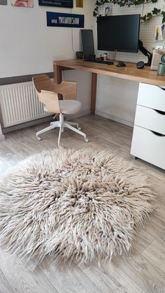 a white rug sitting on top of a hard wood floor next to a computer desk